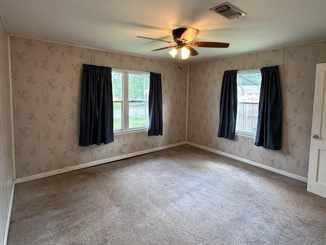 unfurnished room with visible vents, ceiling fan, carpet floors, and plenty of natural light