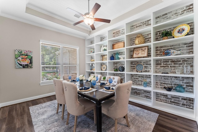 dining space featuring ornamental molding, dark wood-style flooring, a raised ceiling, and baseboards