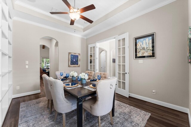 dining room featuring arched walkways, wood finished floors, ornamental molding, ceiling fan, and baseboards