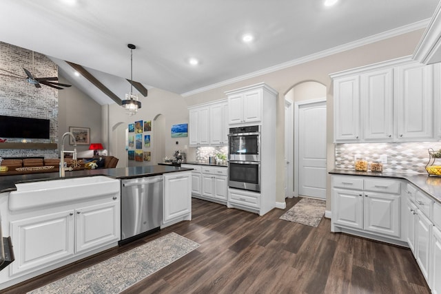 kitchen with stainless steel appliances, open floor plan, arched walkways, and a sink