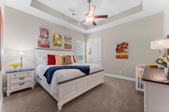 carpeted bedroom featuring visible vents, baseboards, ceiling fan, and a tray ceiling
