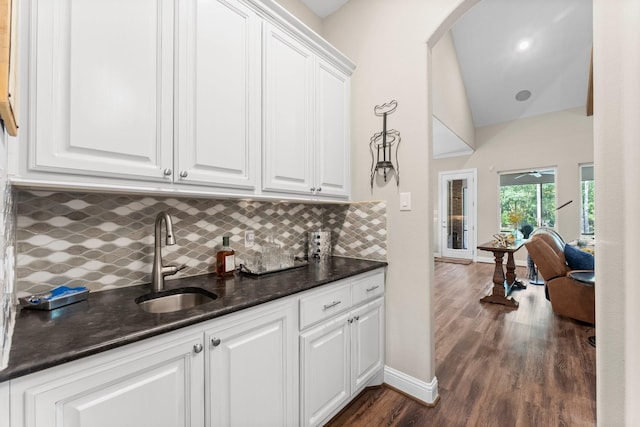 bar with a sink, baseboards, decorative backsplash, and dark wood finished floors