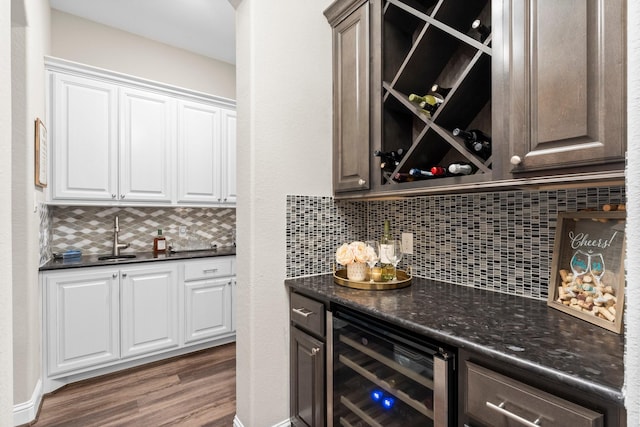 bar with tasteful backsplash, a sink, beverage cooler, wood finished floors, and wet bar