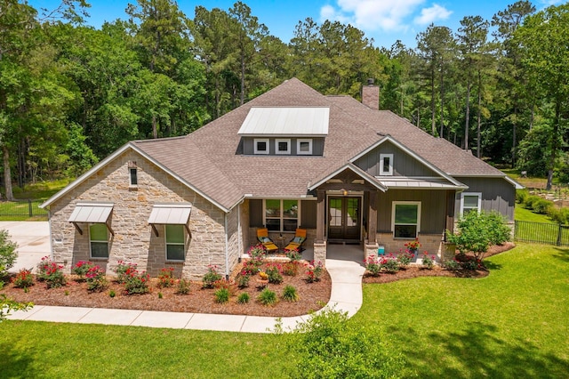 craftsman-style home with a chimney, fence, a shingled roof, stone siding, and a front lawn