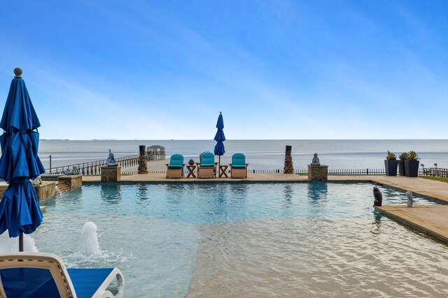 view of pool featuring an infinity pool, fence, a water view, and a patio area