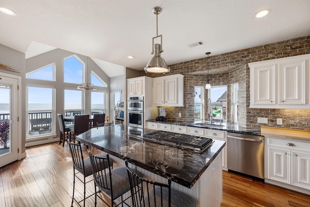 kitchen with visible vents, stainless steel appliances, backsplash, and a sink