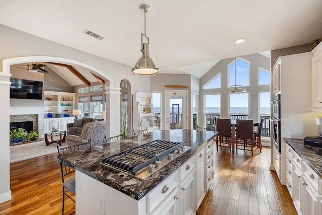 kitchen featuring stainless steel appliances, a kitchen breakfast bar, a ceiling fan, visible vents, and wood finished floors