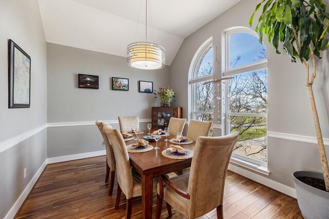 dining space featuring a healthy amount of sunlight, vaulted ceiling, wood finished floors, and baseboards