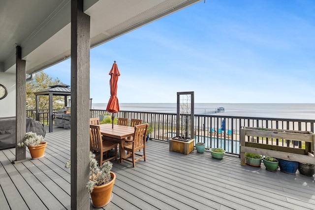 wooden deck featuring outdoor dining space, a gazebo, and a water view