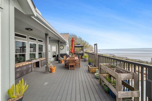 wooden deck featuring a gazebo, outdoor dining area, and a water view