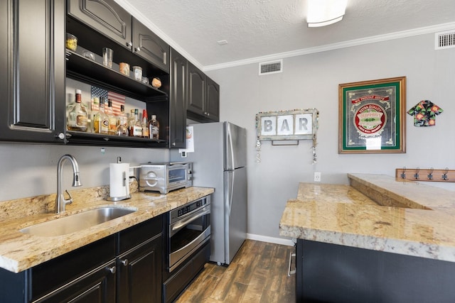 kitchen with crown molding, a sink, appliances with stainless steel finishes, visible vents, and dark wood-style floors