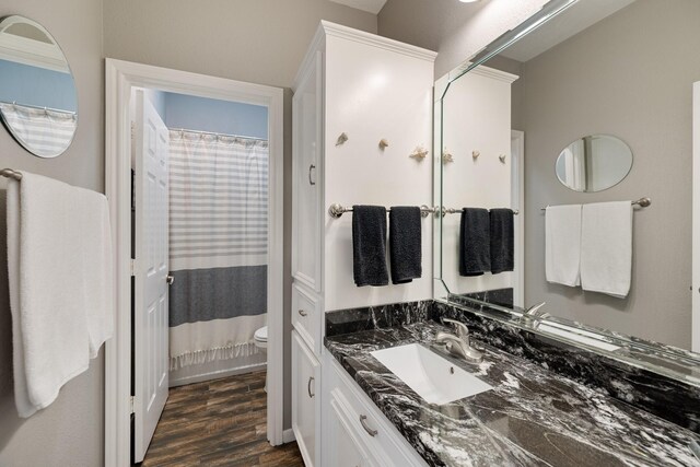 full bath featuring toilet, vanity, curtained shower, and wood finished floors