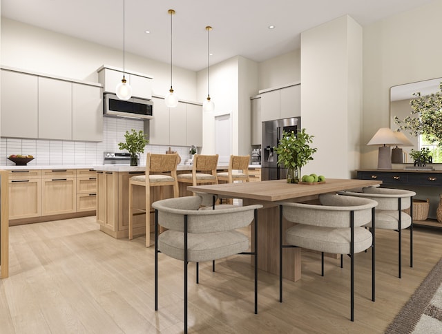 dining area featuring light wood-type flooring, recessed lighting, and a high ceiling