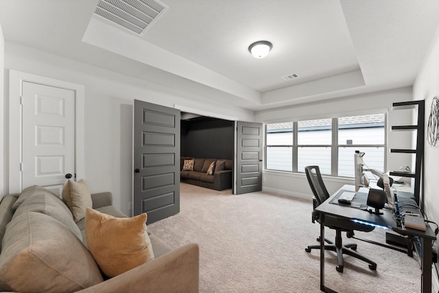 home office featuring light colored carpet, baseboards, visible vents, and a raised ceiling