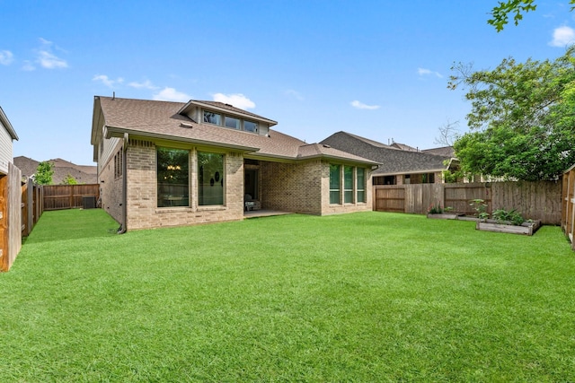 back of house featuring brick siding, a fenced backyard, a yard, and a shingled roof