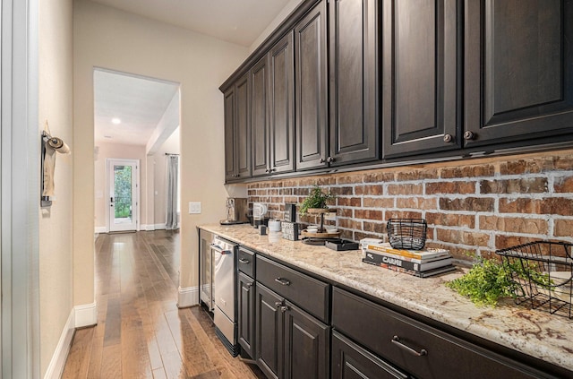 kitchen with baseboards, decorative backsplash, hardwood / wood-style flooring, light stone countertops, and dark brown cabinets