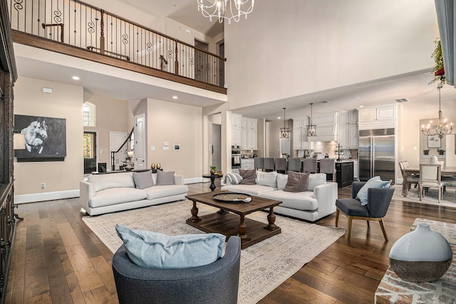 living room featuring a chandelier, a towering ceiling, dark wood-type flooring, stairway, and baseboards