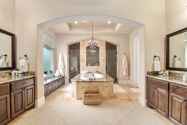 bathroom with a garden tub, vanity, a chandelier, baseboards, and a raised ceiling