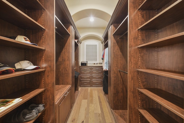 walk in closet with light wood finished floors