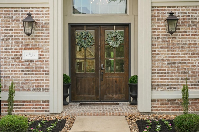 view of exterior entry featuring french doors and brick siding