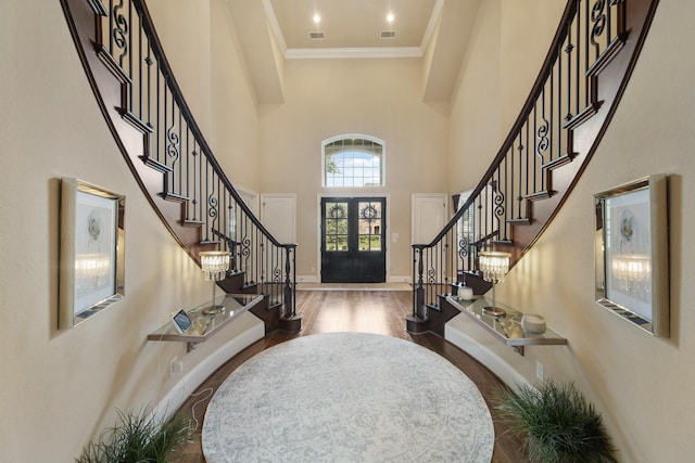 entrance foyer featuring a towering ceiling, wood finished floors, stairway, crown molding, and baseboards