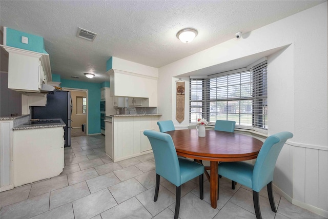 255 Shekel Ln, Houston, TX 77015 - dining space with light tile patterned floors, a wainscoted wall, a textured ceiling, and visible vents