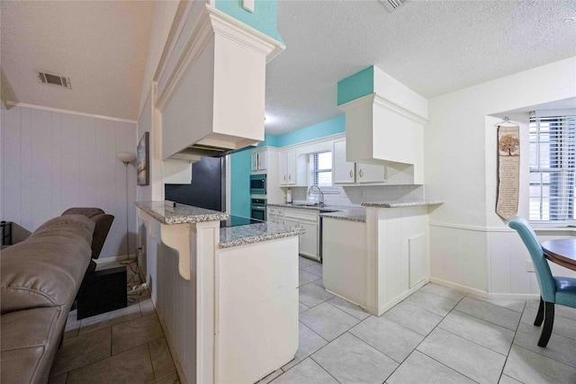 255 Shekel Ln, Houston, TX 77015 - kitchen featuring visible vents, a sink, light stone counters, a peninsula, and stainless steel appliances