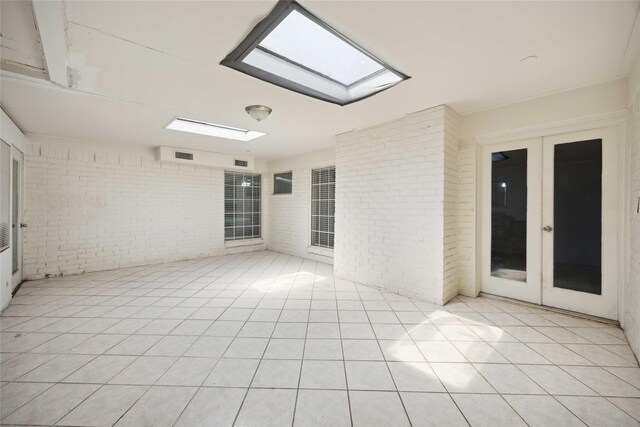 255 Shekel Ln, Houston, TX 77015 - empty room with a skylight, light tile patterned floors, french doors, and brick wall