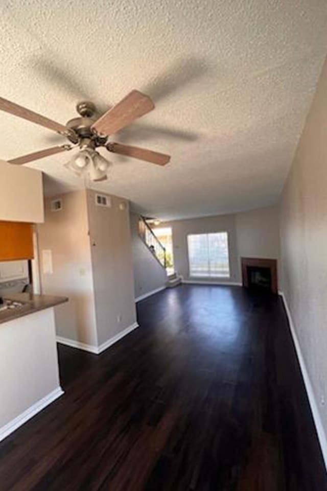 3600 Jeanetta St Unit 2502, Houston, TX 77063 - unfurnished living room with a textured ceiling, a ceiling fan, dark wood finished floors, stairway, and a fireplace