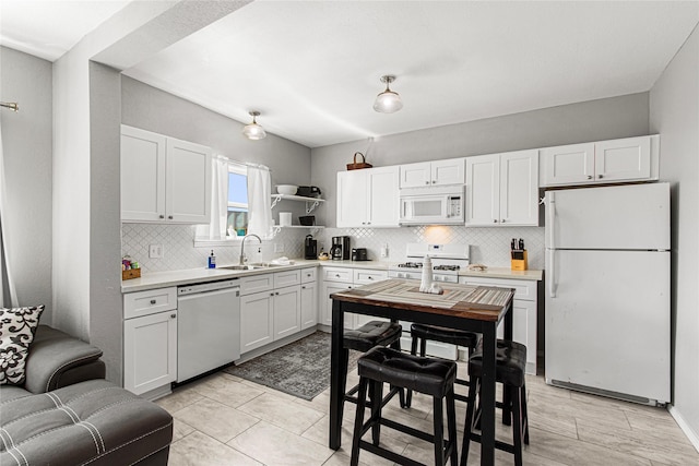 1101 Moody Ave, Galveston, TX 77550 - kitchen with light countertops, a sink, decorative backsplash, and white appliances