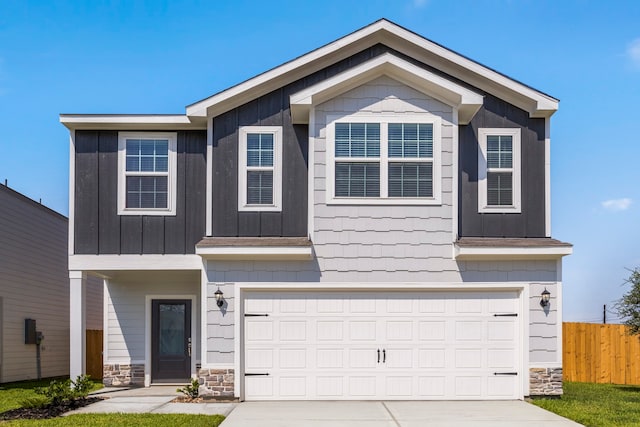 view of front of property with concrete driveway, stone siding, a garage, and fence