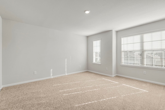 unfurnished room with baseboards and light colored carpet