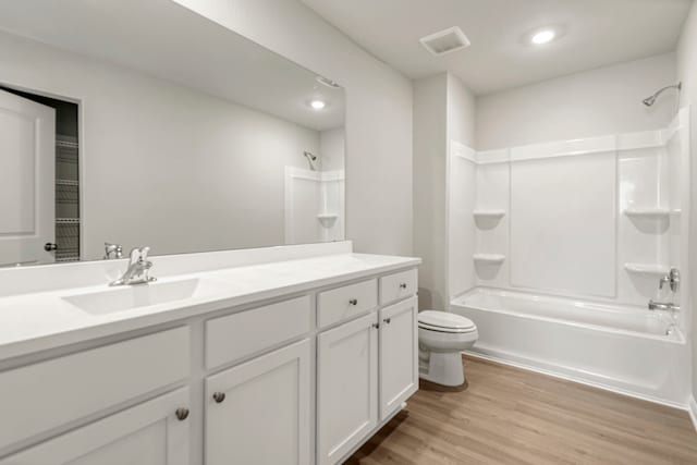 bathroom featuring washtub / shower combination, visible vents, toilet, wood finished floors, and vanity