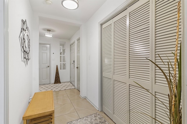 hallway with light tile patterned floors and baseboards
