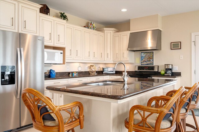 138 Verdia Dr, Crystal Beach, TX 77650 - kitchen with a kitchen island with sink, stainless steel appliances, wall chimney range hood, a kitchen bar, and a sink
