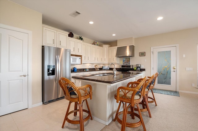 138 Verdia Dr, Crystal Beach, TX 77650 - kitchen featuring a sink, white microwave, stainless steel refrigerator with ice dispenser, wall chimney range hood, and dark countertops
