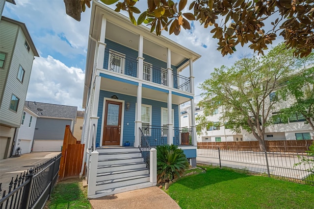 view of front of property featuring a porch, a front lawn, fence private yard, and a balcony