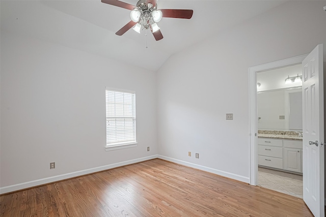 unfurnished bedroom featuring light wood finished floors, ensuite bath, vaulted ceiling, and baseboards