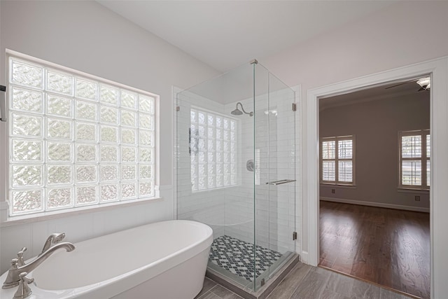 bathroom with wood finished floors, a soaking tub, and a stall shower