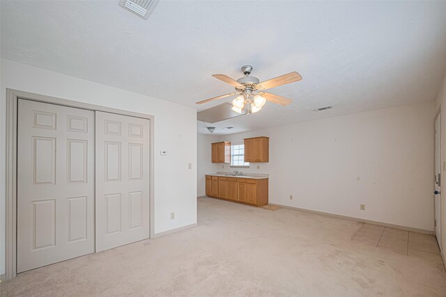 unfurnished living room with a ceiling fan, visible vents, light carpet, and baseboards