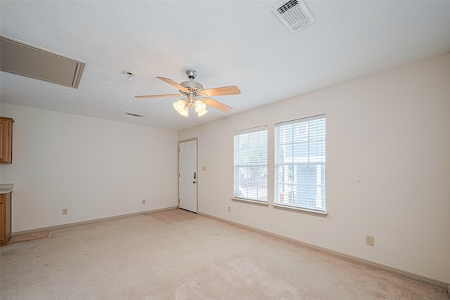 spare room with attic access, visible vents, ceiling fan, and light carpet