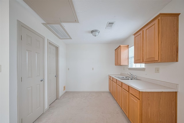 kitchen with a sink, light colored carpet, visible vents, light countertops, and baseboards