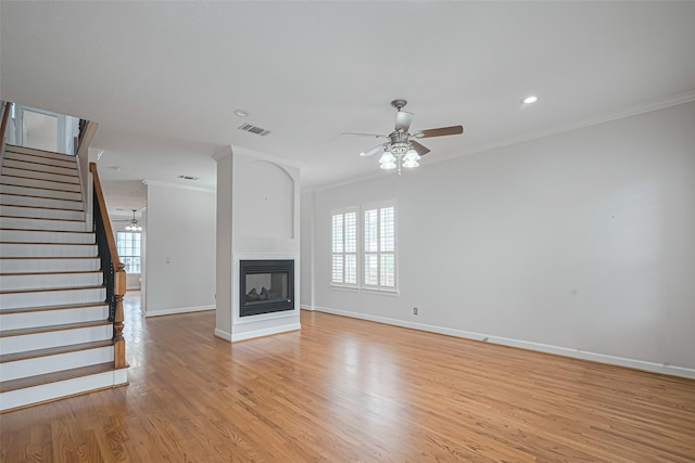 unfurnished living room with stairway, visible vents, plenty of natural light, and ornamental molding