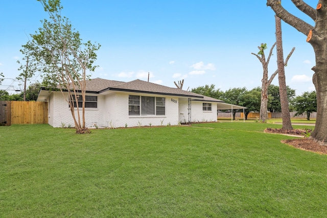 view of front of house with fence, a shingled roof, a front lawn, and brick siding