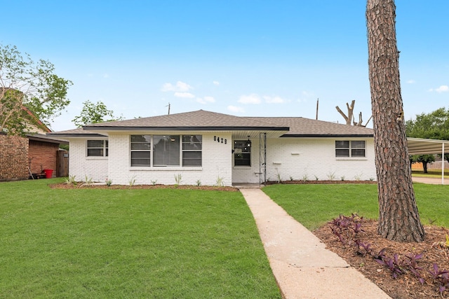 single story home with brick siding, a carport, roof with shingles, and a front lawn