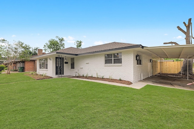 back of property with a lawn, brick siding, a chimney, and a carport