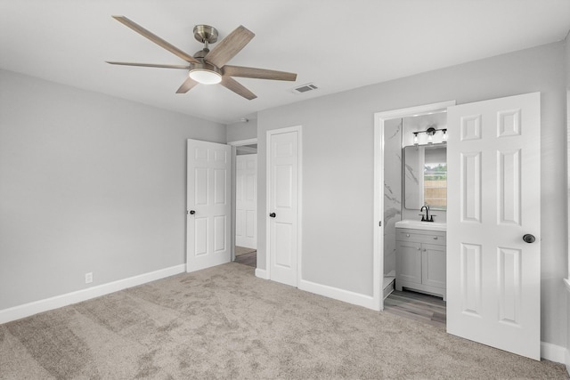 unfurnished bedroom featuring visible vents, a sink, carpet floors, baseboards, and ensuite bathroom