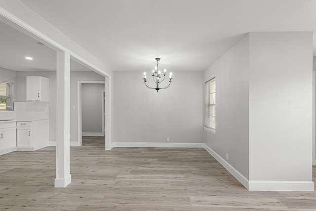 unfurnished dining area with recessed lighting, baseboards, a notable chandelier, and light wood-type flooring