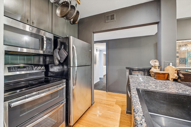kitchen with stainless steel appliances, light wood-style flooring, visible vents, and a sink