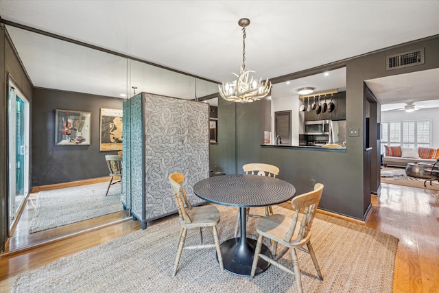 dining room featuring a notable chandelier, visible vents, and wood finished floors